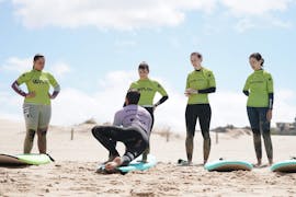 Ein Surflehrer der Wanted Surf School Carcavelos zeigt beim Surfkurs nahe Lissabon einer Gruppe wie man richtig am Brett steht.