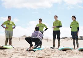 Clases de surf cerca de Lisboa en Carcavelos con Wanted Surf School Carcavelos Uno de los instructores de surf de Wanted Surf School Carcavelos está mostrando a un grupo de amigos cómo surfear durante sus clases de surf cerca de Lisboa.