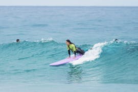 Eine junge Frau reitet bei ihrem privaten Surfkurs nahe Lissabon mit der Wanted Surf School Carcavelos selbstbewusst eine Welle.