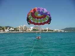 Twee vrienden zitten ontspannen in het harnas en wachten om op te stijgen tijdens het Parasailen in Cala Bona, aangeboden door Sea Sports Mallorca.