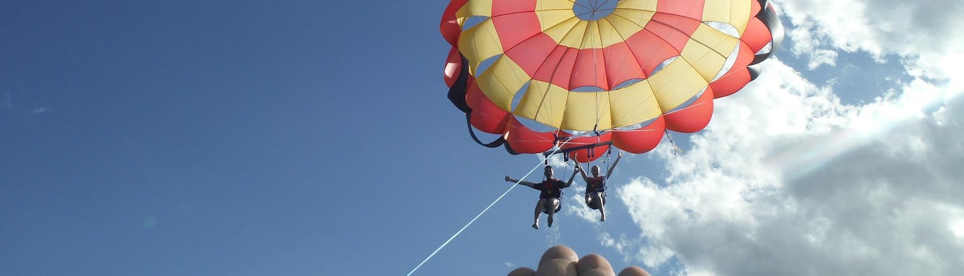 A couple enjoys the flight at an altitude of 100 meters during the Parasailing in Cala Bona, offered by Sea Sports Mallorca.