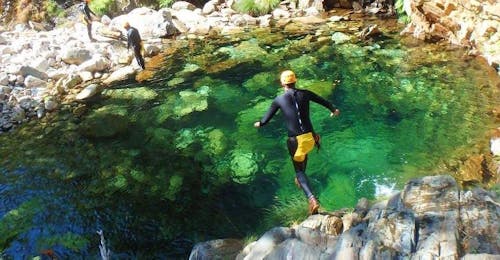Canyoning at Rio Frades in Arouca Geopark with Clube do Paiva Arouca While Canyoning in Rio Frades in Arouca Geopark with Clube do Paiva, a participant jumps into the emerald green water of a natural pool.