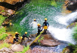 A guide is helping a young boy to prepare for a jump during the Family Canyoning in Ribeira de Vessadas in Arouca Geopark with Clube do Paiva.