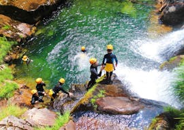 A guide is helping a young boy to prepare for a jump during the Family Canyoning in Ribeira de Vessadas in Arouca Geopark with Clube do Paiva.