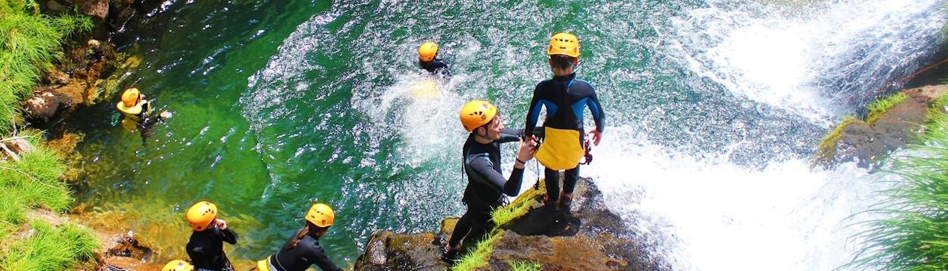Un guía ayuda a un niño a prepararse para un salto durante una excursión de barranquismo familiar en Ribeira de Vessadas en el Geoparque de Arouca con el Clube do Paiva.