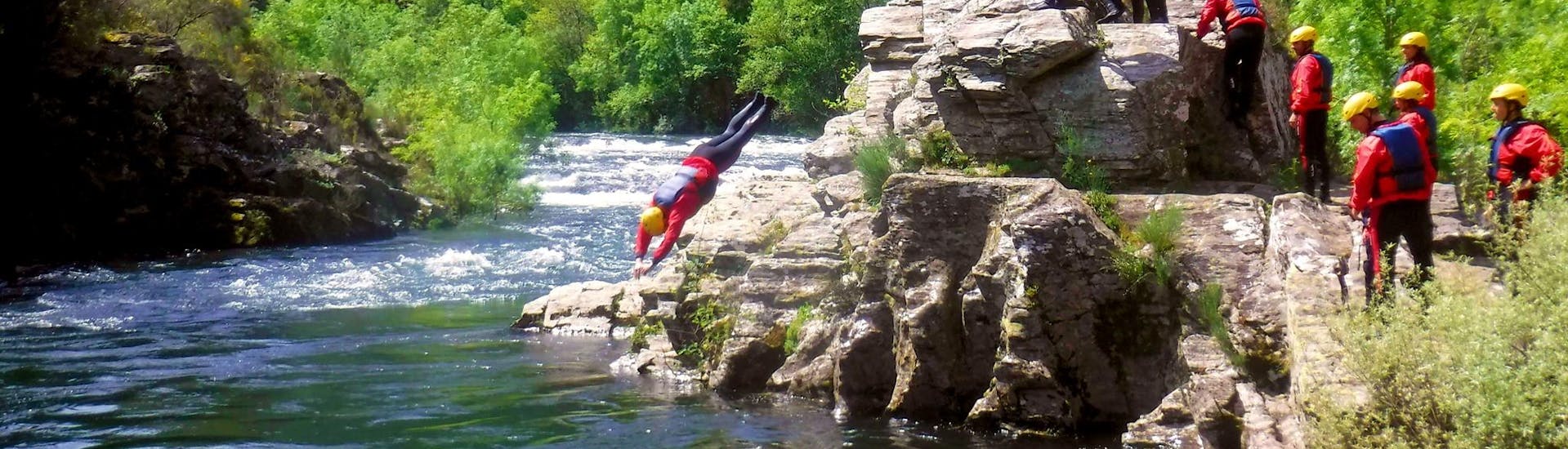 A participant of the Easy River Trekking in Rio Paiva in Arouca Geopark with Clube do Paiva is cliffjumping into the cool water of the river.