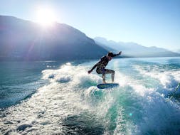 A man is skillfully surfing a wave during his Wakeboard & Wakesurf Lessons on Lake Annecy with Le Spot.