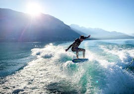 Un homme surfe habilement sur une vague pendant son Cours de wakeboard & wakesurf sur le lac d'Annecy avec Le Spot.