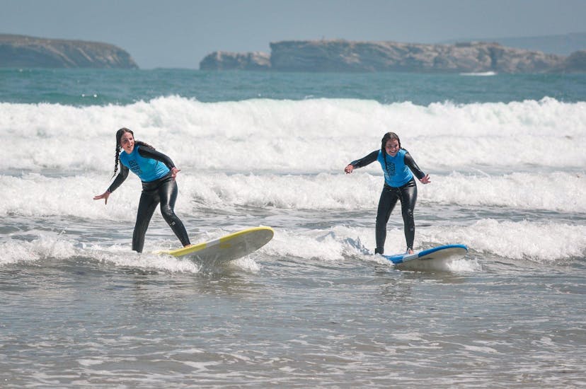 Two friends are surfing their first waves during the Beginner Surf Lessons at Gamboa Beach in Peniche with Go4Surf Peniche.