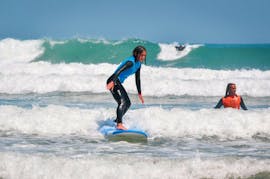 A girl is surfing her first waves during the Beginner Surf Lessons at Gamboa Beach in Peniche with Go4Surf Peniche.
