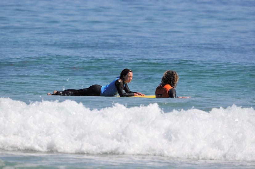 A surf instructor is giving tips for surfing the next wave to his student during the Private Surf Lessons at Gamboa Beach in Peniche with Go4Surf Peniche.