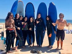 A group of young women and their surf instructros from Lisbon Surfaris are smiling at the camera as they get ready for their surfing lessons on Carcavelos Beach near Lisbon.