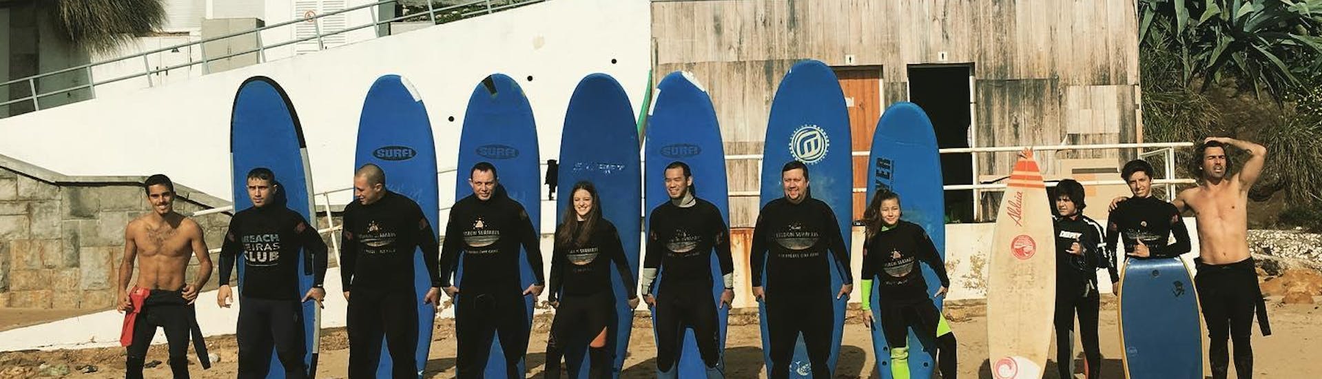 Een groep aspirant-surfers poseren voor een foto naast hun surfinstructeurs van Lisbon Surfaris voordat ze beginnen met hun surflessen op het strand van Carcavelos bij Lissabon.