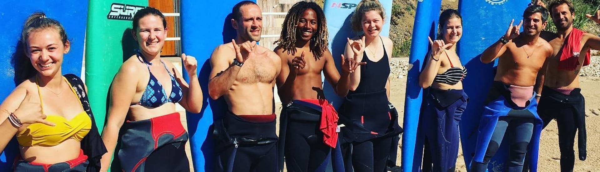 A group of aspiring surfers is posing for a photo alongside their surf instructors from Lisbon Surfaris before they get started with their private surfing lessons on Carcavelos Beach near Lisbon.