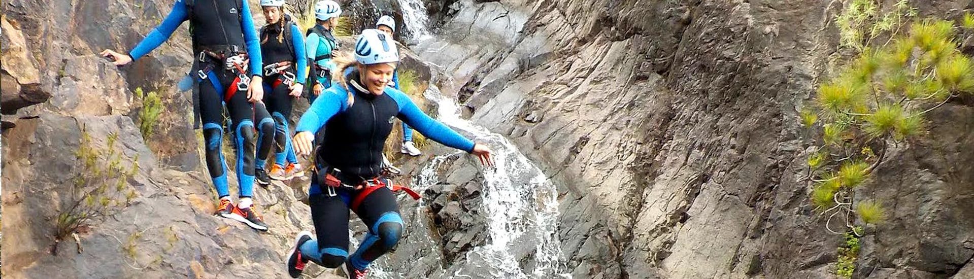 During the Canyoning at Barranco de los Cernícalos in Gran Canaria a woman jumps from the cliff into the water under the supervision of the guide from Mojo Picón Aventura.