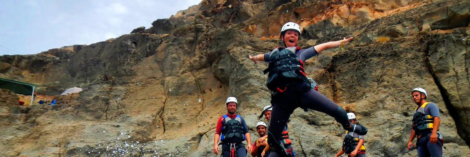 During the Coasteering at the South Coast of Gran Canaria a woman jumps from a rock into the crystal clear sea, under the supervision of a guide from Mojo Picón Aventura.