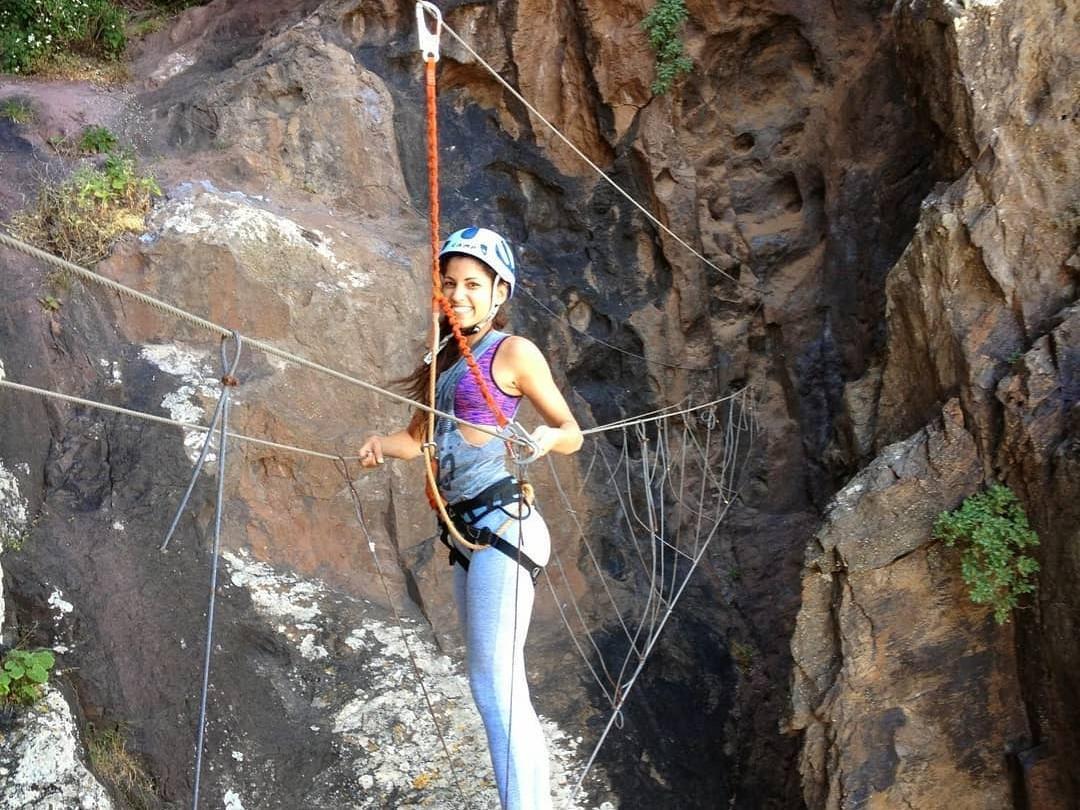 A woman skillfully overcomes the obstacle during the Vía Ferrata at Barranco de Berriel in Gran Canaria organised by Mojo Picón Aventura.