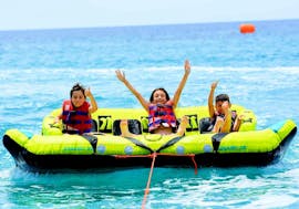 Tre bambini si divertono molto durante il loro Giro in Crazy Sofa alla Spiaggia di Kamari a Santorini organizzato da Kamari Beach Watersports Santorini.
