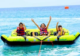 Tre bambini si divertono molto durante il loro Giro in Crazy Sofa alla Spiaggia di Kamari a Santorini organizzato da Kamari Beach Watersports Santorini.