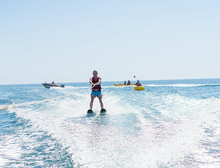 With the help of a certified instructor from Kamari Beach Watersports Santorini, a young man is waterskiing at Kamari Beach in Santorini.