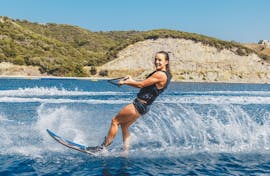 A young woman is wakeboarding at Kamari Beach in Santorini with the help of an experienced instructor from Kamari Beach Watersports Santorini.
