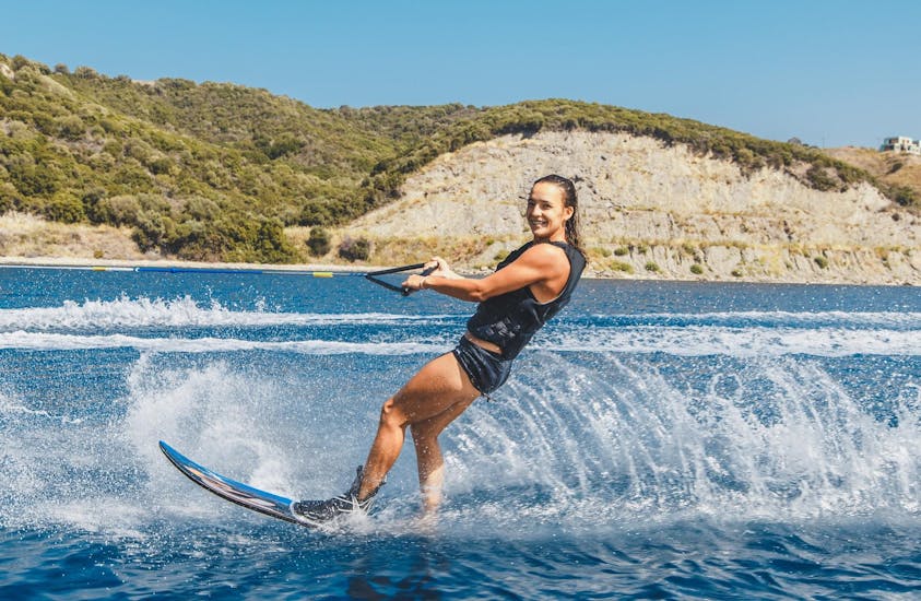 A young woman is wakeboarding at Kamari Beach in Santorini with the help of an experienced instructor from Kamari Beach Watersports Santorini.