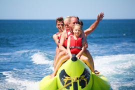 Eine Familie genießt ihre Fahrt auf dem Bananenboot während einer Spaßbootfahrt an der Praia de Armação de Pêra mit Moments Watersports Algarve.