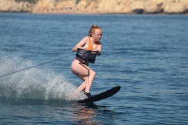 Una chica montada en su tabla mientras hace ski acuático en Praia Armação de Pêra con Moments Watersports.