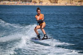 Una mujer montando en su tabla mientras hace wakeboard en Praia Armação de Pêra con Moments Watersports.