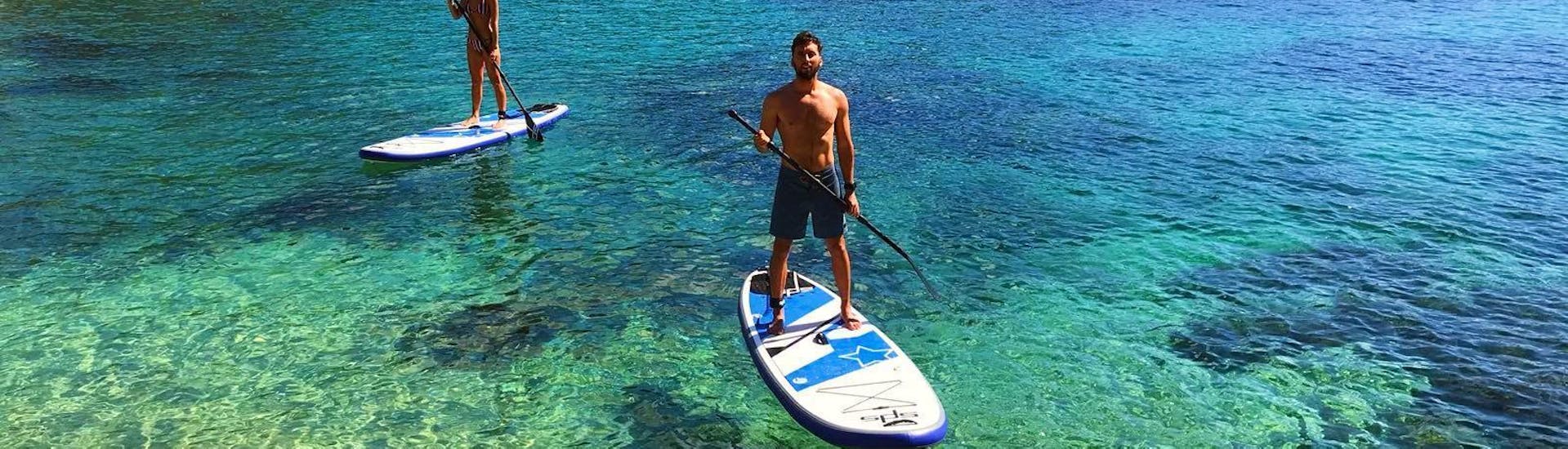 Ein Mann paddelt entspannt durch das glasklare Gewässer und genießt die Aussicht während der SUP Tour zu Buchten und Höhlen in Ibiza mit Mediterrania Paddle Surf Ibiza. 