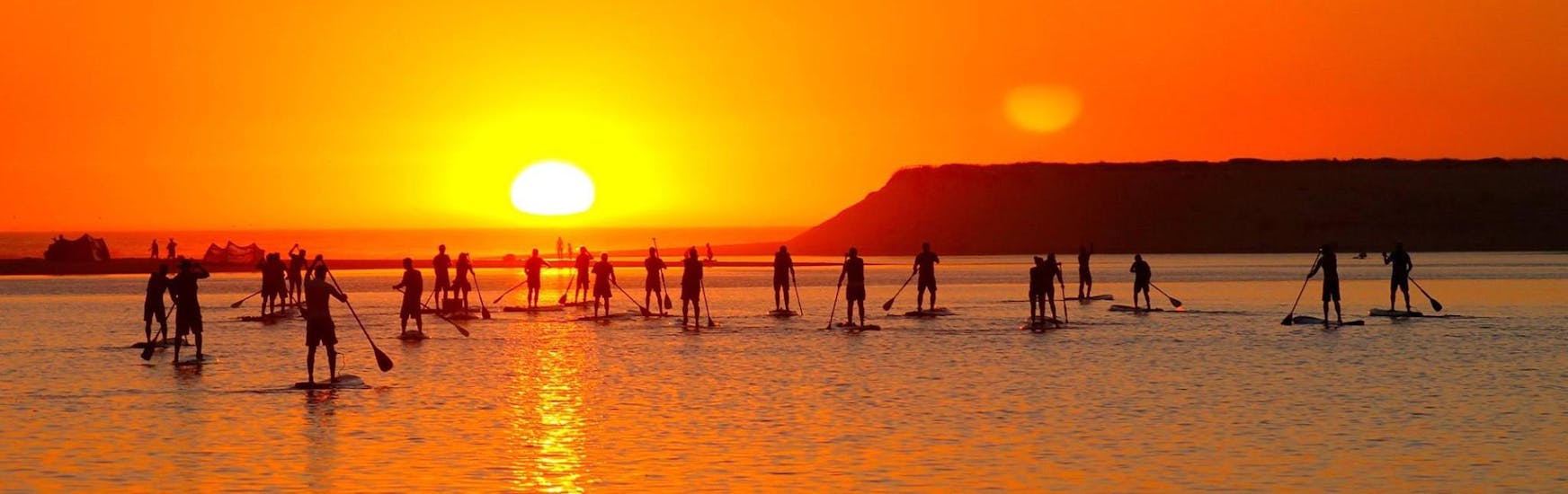 Die Teilnehmer des SUP-Kurses an der Lagoa de Albufeira in Sesimbra mit Meira Pro Sesimbra paddeln gemeinsam in den Sonnenuntergang.