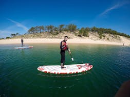 Two participants of the Private SUP Lessons at Lagoa de Albufeira in Sesimbra with Meira Pro Center Sesimbra are paddling in the calm water of the lagoon.