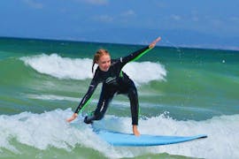 A young girl is surfing her first waves during the Surfing Lessons at Praia da Lagoa de Albufeira in Sesimbra with Meira Pro Center Sesimbra.