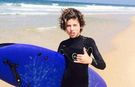 Ein Junge posiert während seines privaten Surfkurses an der Praia da Lagoa de Albufeira mit dem Meira Pro Center Sesimbra für ein Foto mit seinem Surfbrett.