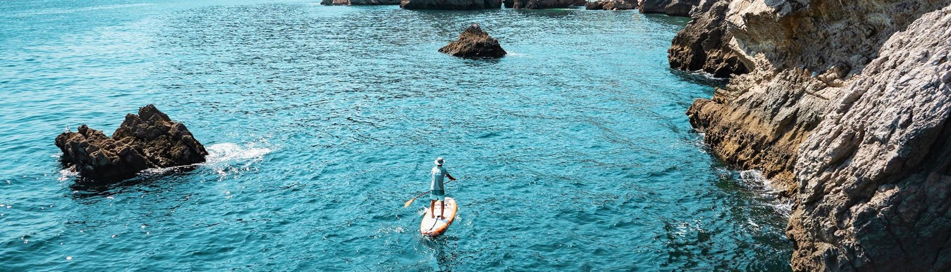 A participant of the Boat & SUP Safari in Arrábida Natural Park from Sesimbra organized by Meira Pro Center Sesimbra is exploring the stunning limestone coast on his SUP-Board.