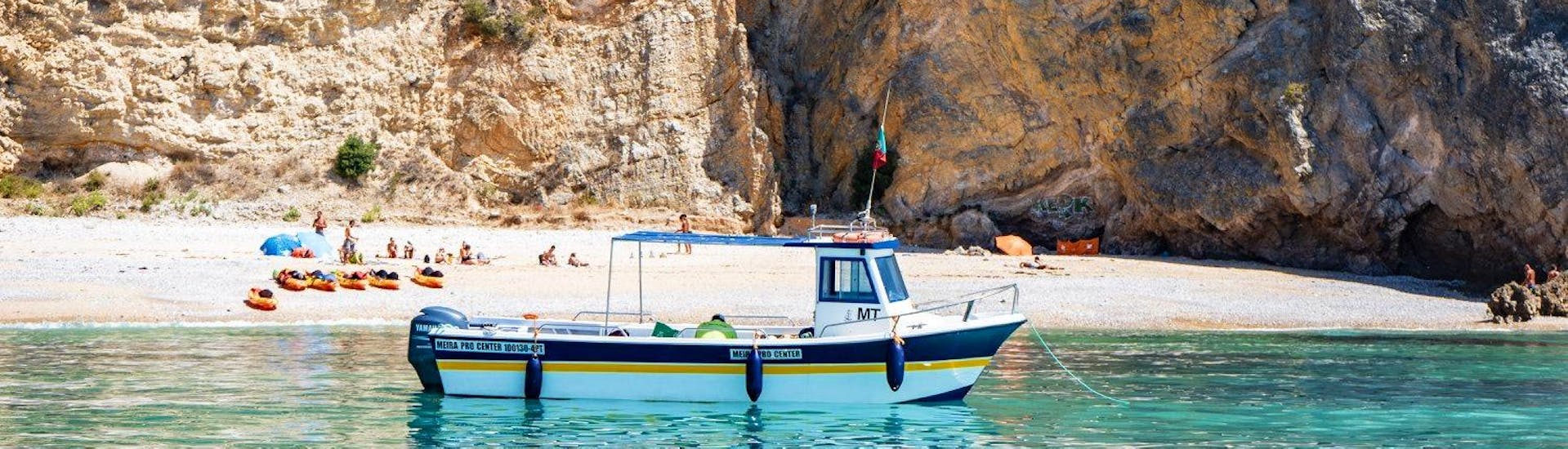 Während der Bootstour zu den wilden Stränden des Arrábida Naturparks mit Meira Pro Center Sesimbra liegt das Boot vor einem Strand , wo die Teilnehmer sich entspannen und das klare Wasser genießen können.