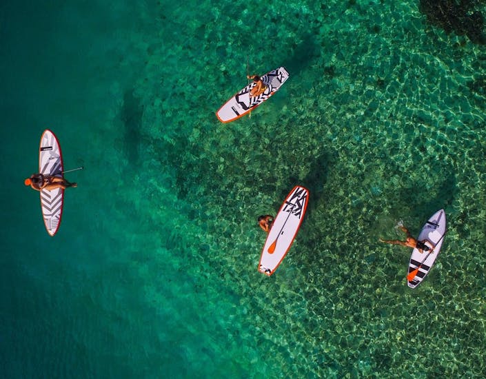 A group of friends is enjoying the clear water during their SUP Rental at Lagoa de Albufeira in Sesimbra from Meira Pro Center Sesimbra.