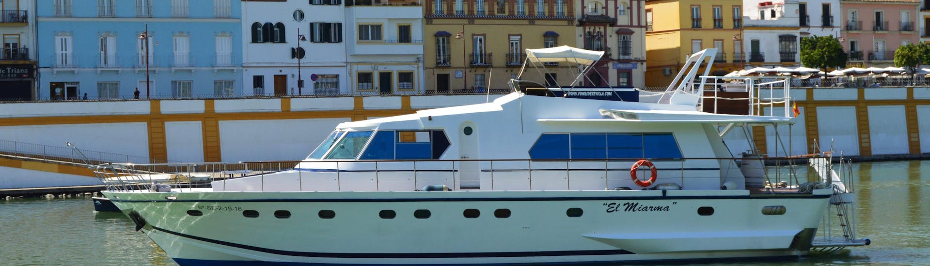The tour participants admire the colourful buildings and the natural landscape during their Luxury Boat trip on the Río Guadalquivir with 6-course menu with Fun Ride Sevilla.