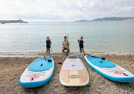 Stand Up Paddling Vermietung in Jávea mit Siesta Advisor Jávea Ein Vater bereitet sich gemeinsam mit seinen Kindern am Strand für seine Tour vor, dank dem SUP Verleih in Jávea von Siesta Advisor Jávea.