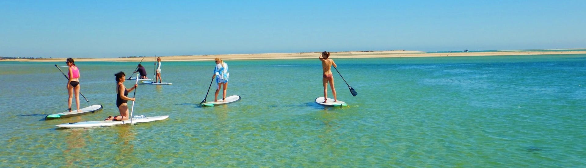 During a Guided SUP Tour in Ria Formosa Natural Park with Kite Culture Algarve, a group of friends is exploring the turquoise, warm waters of the lagoon.