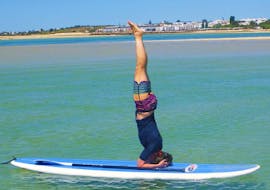 During the Sunset SUP Yoga at Praia da Fuseta with Kite Culture Algarve, a participant is practicing a headstand on the SUP board.