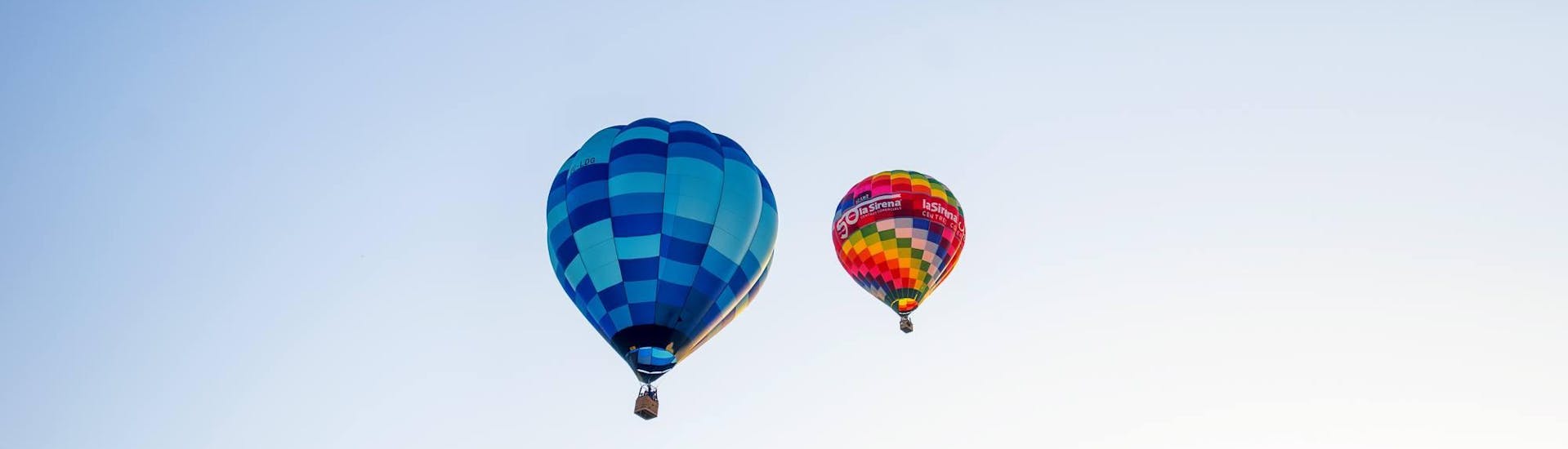 Die Flugteilnehmer beobachten einen anderen Heißluftballon und genießen die wundervolle Aussicht mit dem Piloten von Ibiza en Globo während ihrer Ballonfahrt über Ibiza ab San Rafael.