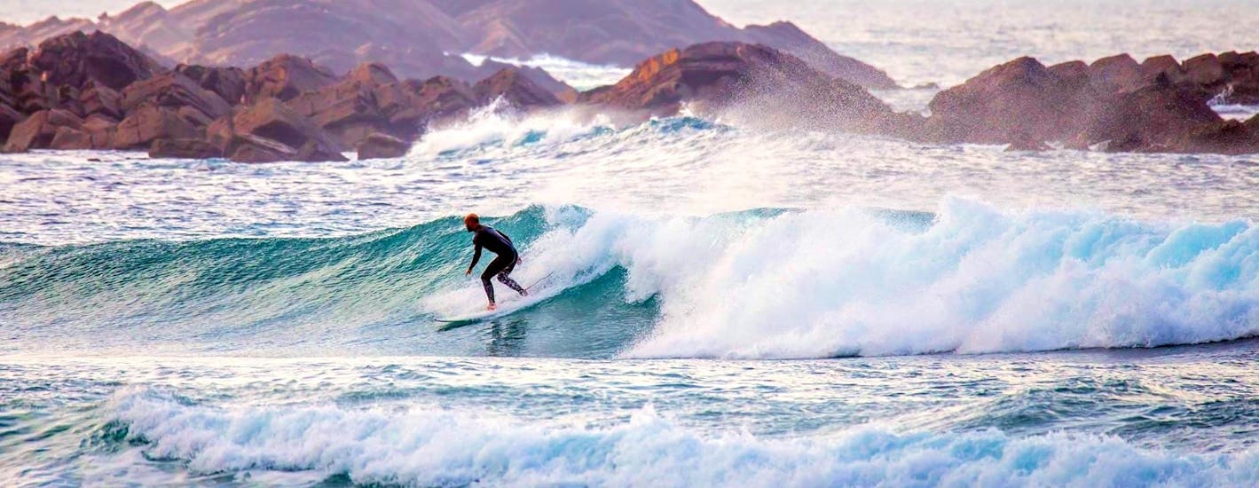 Un participante de las clases de surf en la Costa Vicentina está mejorando sus habilidades de surf en el Algarve, con la ayuda de un instructor de Neptunos Surf School Algarve."
