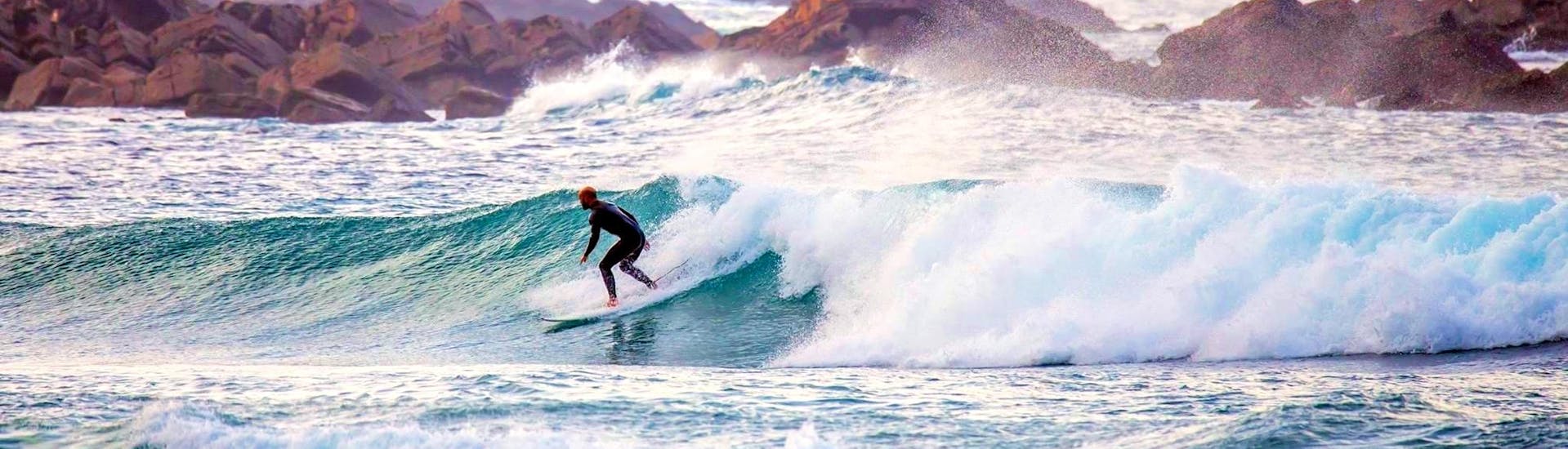 Un participante de las clases de surf en la Costa Vicentina está mejorando sus habilidades de surf en el Algarve, con la ayuda de un instructor de Neptunos Surf School Algarve."