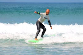 A participant of the Surfing Lessons on the Costa Vicentina with Pick-Up is learning how to surf in the Algarve with the help of an instructor from Neptunos Surf School Algarve.