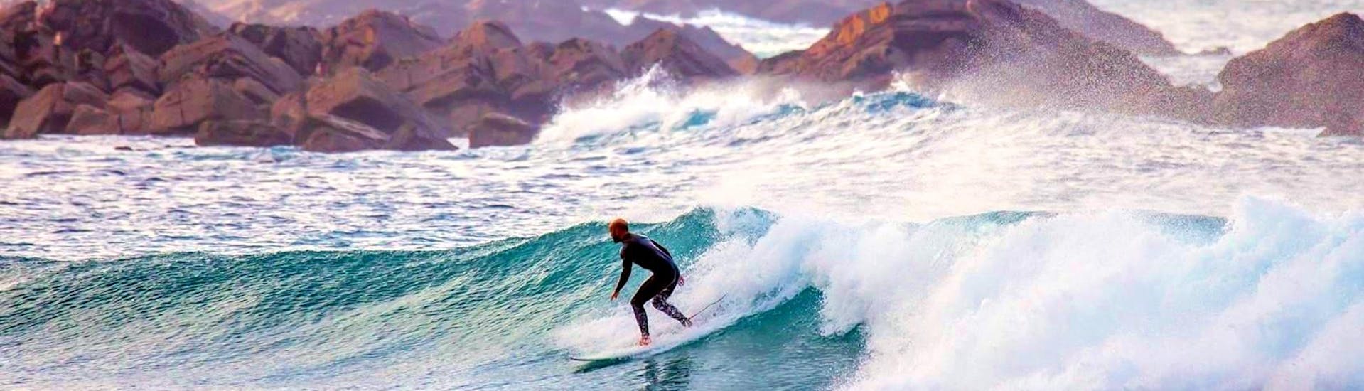 Ein Surfer reitet die besten Welllen der Algarve während, er mit seinem Surf Guide an derCosta Vicentina mit Transfer von Neptunos Surf School Algarve unterwegs ist.