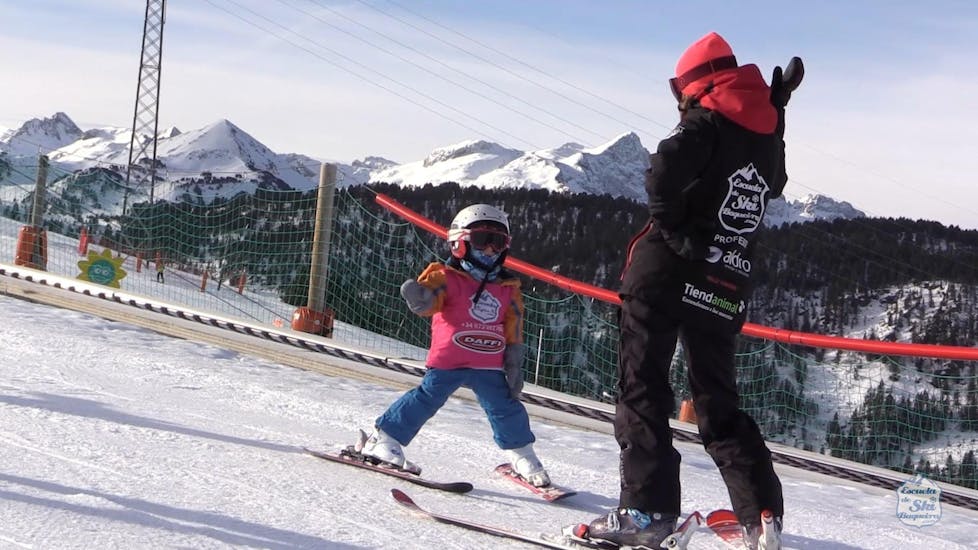 Een kind maakt zijn eerste pogingen op de piste samen met een skileraar van Escuela Ski Cerler binnen de privéskilessen voor kinderen voor alle niveaus en leeftijden.