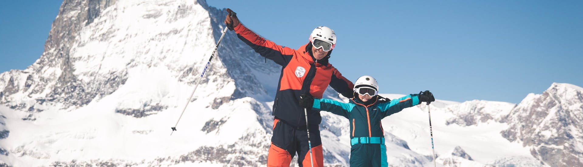Een skileraar en een kind juichen tijdens de Kids Skilessen (6-11 j.) voor alle niveaus.