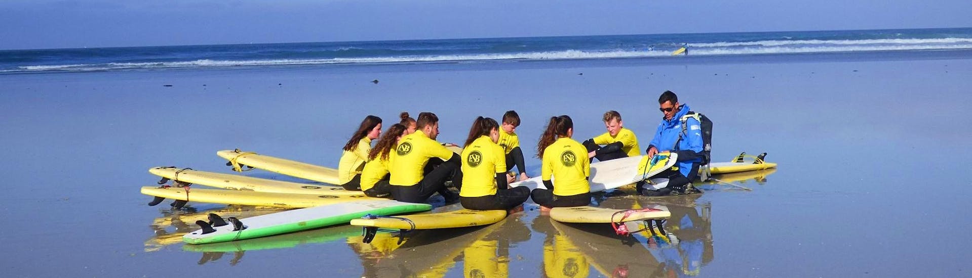 The instructor is giving safety instructions on the beach during the surfing lessons in la pointe de la torche for all levels with ESB la torche.