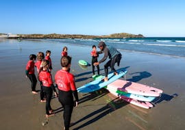 The instructor is showing how to stand up on the board during the surfing lessons in la pointe de la torche for all levels with ESB la torche.
